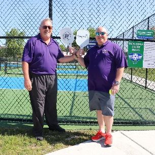 photo of village president Puccio and board president Ludwig holding paddles and smiling