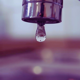 close up of faucet with water drop leaking