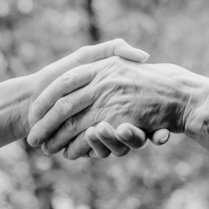 black and white photo of two hands holding in symbol of help