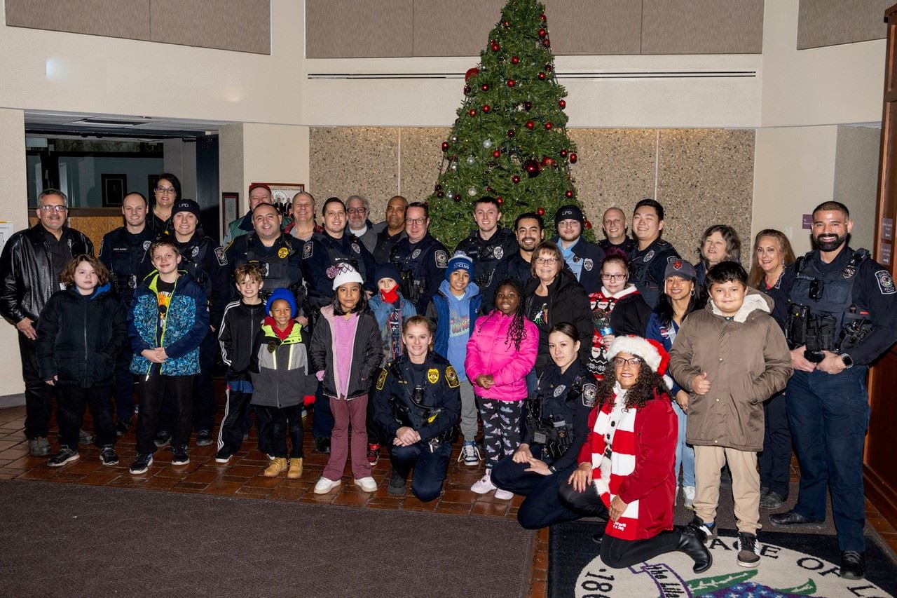Group photo of LPD Officers, LPCAAA members and participating children inside Lombard Village Hall